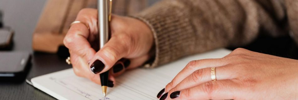 crop woman writing down notes in diary