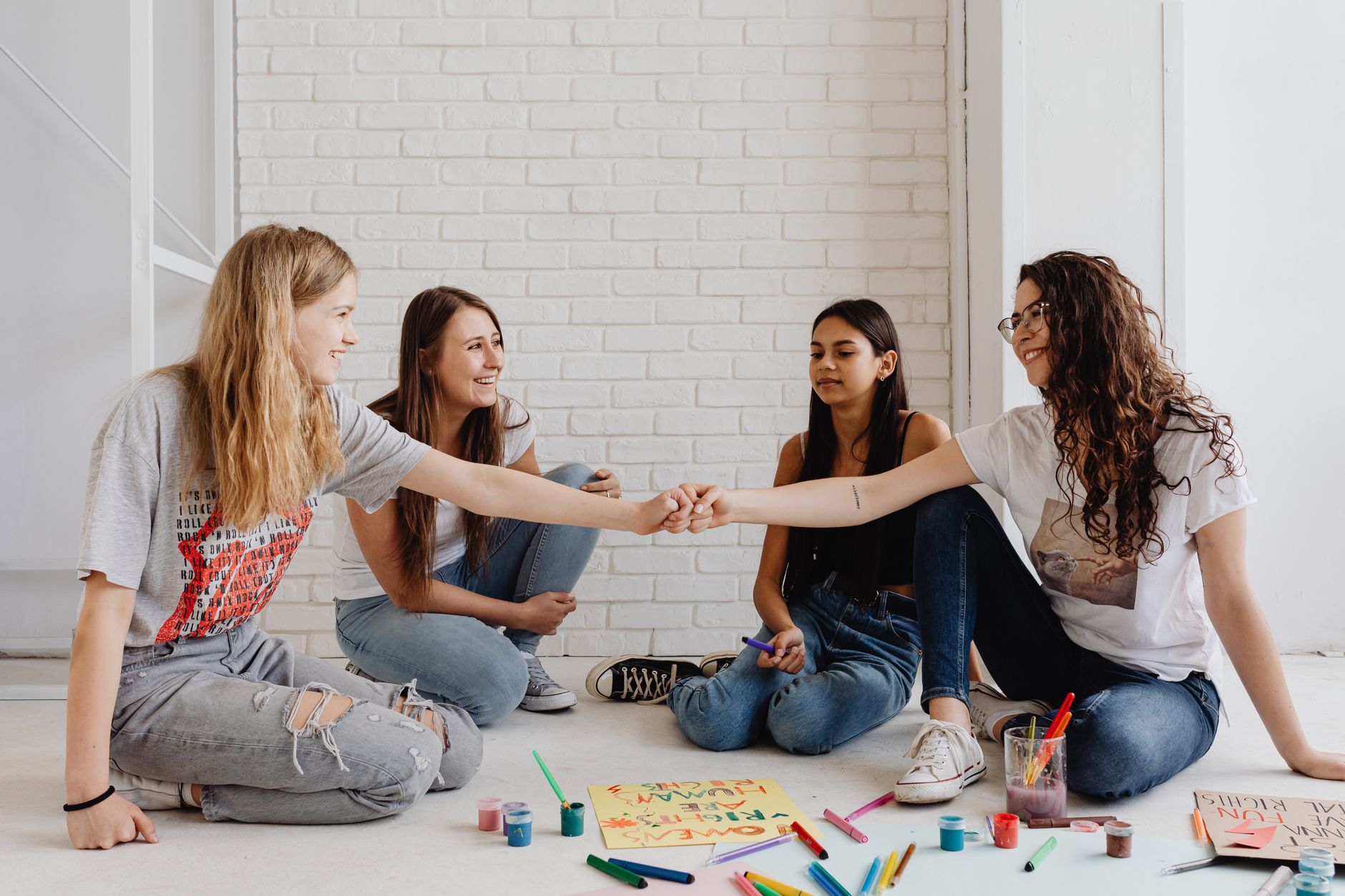two teens and two young women drawing on the floor